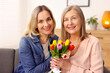 © New Africa - Smiling woman with bouquet of tulips and her daughter at home. Happy Mother's Day