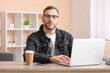 © Pixel-Shot - Young man sitting at workplace and using laptop at home