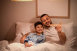 © Pixel-Shot - Father and his little son playing with wooden airplane before bedtime at home