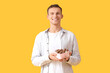 © Pixel-Shot - Happy young man with delicious chocolate candies on yellow background