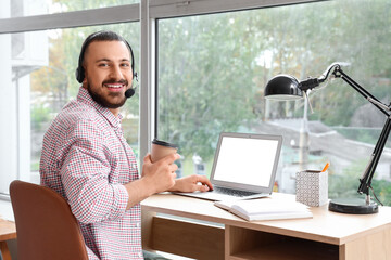 Wall Mural - freelancer sitting at workplace with headset and cup of coffee at home