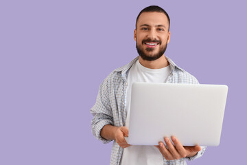 Wall Mural - young man with laptop on lilac background