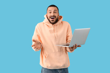 Wall Mural - emotional young man with laptop on blue background
