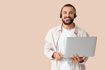 Wall Mural - young man with headset and laptop on beige background