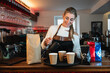 © Thilo Wagner - Young blonde barista pouring fresh coffee into paper cups at a café counter