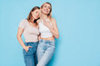 © halayalex - Two young beautiful smiling brunette and blond hipster female in trendy summer clothes. Lovely women posing on blue background in studio. Positive models having fun. Cheerful and happy. isolated