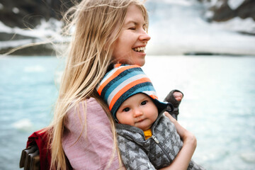 Wall Mural - mother traveling with infant baby in mountains family mom and child having fun hiking outdoor togeth
