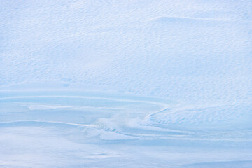 Wall Mural - blue wavy lines in ice on snow-covered frozen ice surface