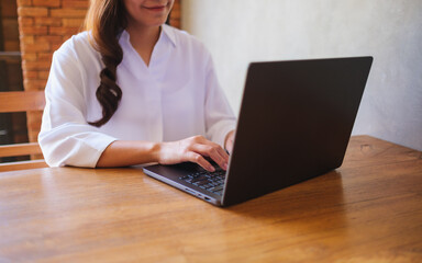 Wall Mural - closeup image of a woman working and typing on laptop computer keyboard