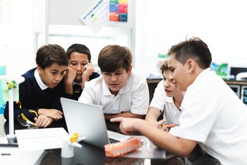 Fototapete - Group of student boys focus on laptop, collaborate in classroom. Boys in school uniforms teamwork, learn together, discuss ideas in classroom. Student focus on group project, work together on laptop