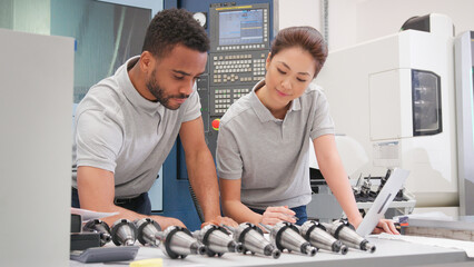 Wall Mural - male and female engineers discussing plans for job whilst looking at laptop