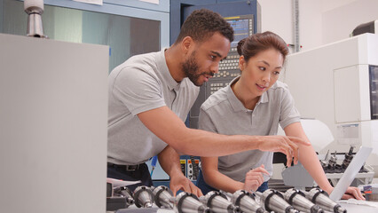 Wall Mural - male and female engineers discussing plans for job whilst looking at laptop