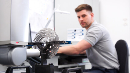 Wall Mural - male engineer uses cmm coordinate measuring machine in factory with focus on foreground