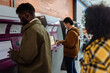 © bernardbodo - Passengers purchasing train tickets at self-service kiosk in subway station