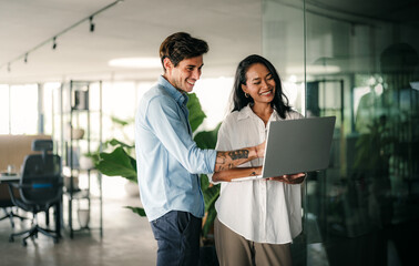 Multiracial colleagues discussing startup project and smiling during workday in office interior