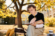 © LIGHTFIELD STUDIOS - Stylish young man studying under a beautiful tree on a sunny autumn day