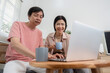 © wichayada - Senior couple enjoying coffee while exploring content on a laptop at home.
