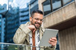 © Srdjan - Young hipster businessman with cool attitude standing out of office building working digital tablet. Expatriate business person standing out of the crowd, intelligent design professional occupation.