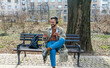 © Srdjan - Young hipster businessman with cool attitude sitting in the park having video call on digital tablet. Expatriate business person standing out of the crowd, intelligent design professional occupation.