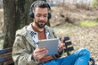 © Srdjan - Young hipster businessman with cool attitude sitting in the park having video call on digital tablet. Expatriate business person standing out of the crowd, intelligent design professional occupation.