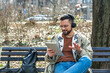© Srdjan - Young hipster businessman with cool attitude sitting in the park having video call on digital tablet. Expatriate business person standing out of the crowd, intelligent design professional occupation.