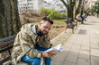 © Srdjan - Young curious religious man, reading a book about religion, while sitting in the park on bench. Finding God male, happy and hungry for knowledge about faith. Christian or muslim read Bible or Quran.