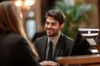 © ryker - hotel front desk staff member engages with guest during check in, showcasing friendly atmosphere. staff member is dressed in formal attire, smiling warmly