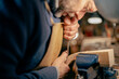 © august.columbo - Luthier crafting violin scroll in workshop using precision tools