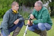 © auremar - young gardener being shown how to operate a strimmer