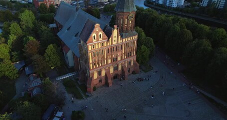 Wall Mural - A stunning aerial view of Kaliningrad Cathedral on Kant Island, captured by a drone. The red-brick Gothic structure stands among lush greenery, with a clock tower. 