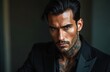 © Vadym - Portrait of tanned seductive man with tattoo on his neck wearing luxurious black suit. Attractive macho guy gazes intently. Charismatic italian billionaire boss looking seriously on camera.