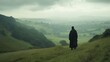 © Diffin - A man in a long coat stands on a hill, gazing over a vast valley below.