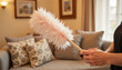 © Olesia - Person cleaning with a feather duster in a cozy living room