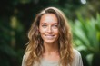 © Pavel Lysenko - With a radiant smile, a young woman stands amidst lush green foliage, capturing the serene beauty of nature. The warm light enhances her vibrant presence in this tranquil setting