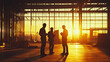 © cs - Silhouetted construction workers discussing plans during sunset in an industrial setting