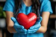 © SimpleDesignStudio - Female Healthcare Worker in Gloves Holding a Red Heart Symbolizing Care and Compassion for Patients in a Medical Environment