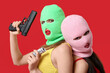 © Pixel-Shot - Beautiful young stylish women in balaclavas and swimsuits holding money with gun on red background