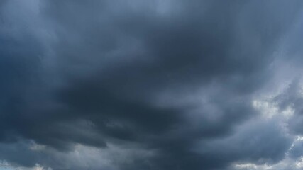 Wall Mural - A dramatic sky time-lapse filled with dark, heavy clouds. The deep blue and gray tones suggest an approaching storm, creating a sense of tension and anticipation in the atmosphere. Timelapse.
