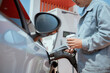 © 2B - Man refuels car while holding a beverage at a modern gas station in bright daylight