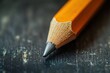© Nyxoria - Close-up view of an orange pencil with a sharpened tip resting on a dark wooden surface