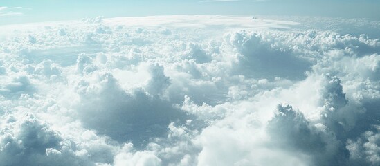 Poster - Fluffy white clouds scattered across a bright blue sky with soft sunlight illuminating the scene from above creating a serene atmosphere.