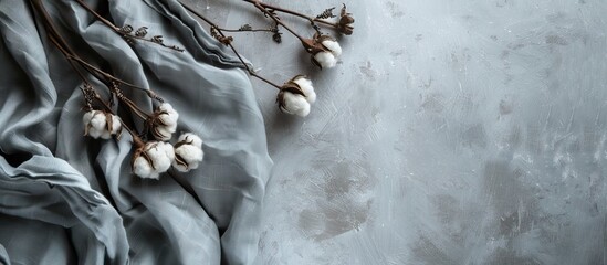 Poster - Cotton fabric draped on concrete background with white cotton branch on the left side creating ample copy space in soft neutral tones