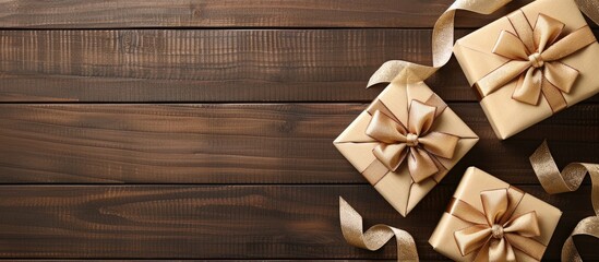 Poster - Top view of three neatly arranged gift boxes with beige ribbons on a dark wooden surface featuring ample copy space on the left side