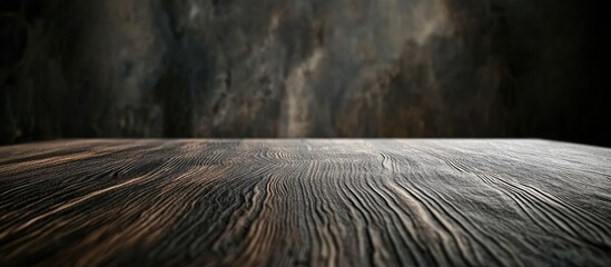 Leinwandbilder - Grainy wooden table surface with detailed texture in foreground; blurred dark stone wall backdrop creates depth and contrast in image.