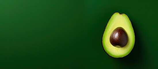 Poster - Sliced avocado with a dark brown pit on a rich green background featuring ample copy space on the left side for design purposes.