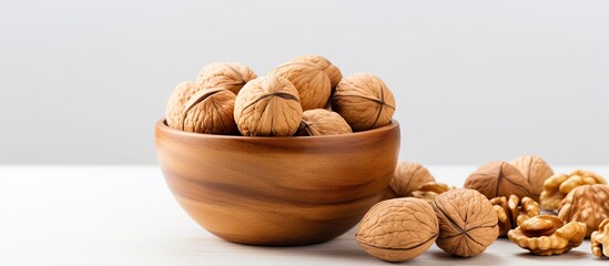 Poster - Brown wooden bowl filled with whole walnuts on a light background with scattered walnuts and ample copy space for text placement