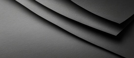 Poster - Black textured paper sheets with varying heights overlapping each other on a dark background, creating depth and contrast in monochrome tones.