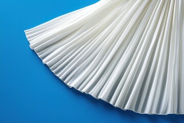 Fototapete - Pleated white fabric drapes elegantly over a vibrant blue surface, showcasing its texture and movement