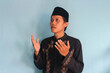 © Lailar Studio - Young Asian Muslim man raises hands with prayer gesture
