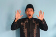 © Lailar Studio - Surprised young asian muslim man wearing a songkok raised hand with open mouth